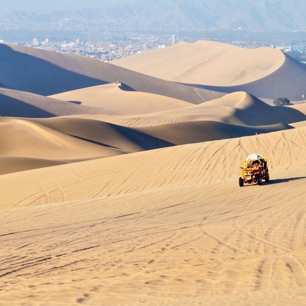 Dune buggy crossing the vast sand dunes of Huacachina Oasis during an exciting desert adventure in Peru.