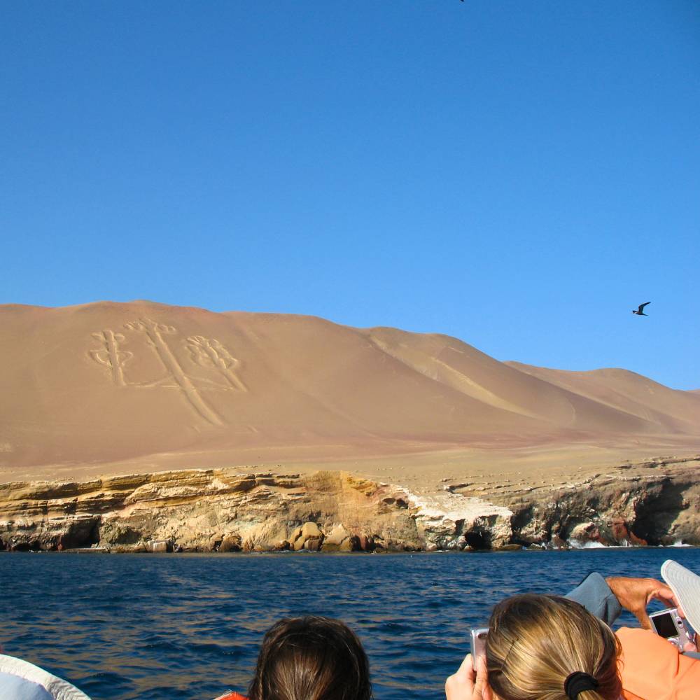 Tourists visiting the mysterious Candelabra geoglyph in Paracas Bay during a Ballestas Islands boat tour from Lima, Peru.