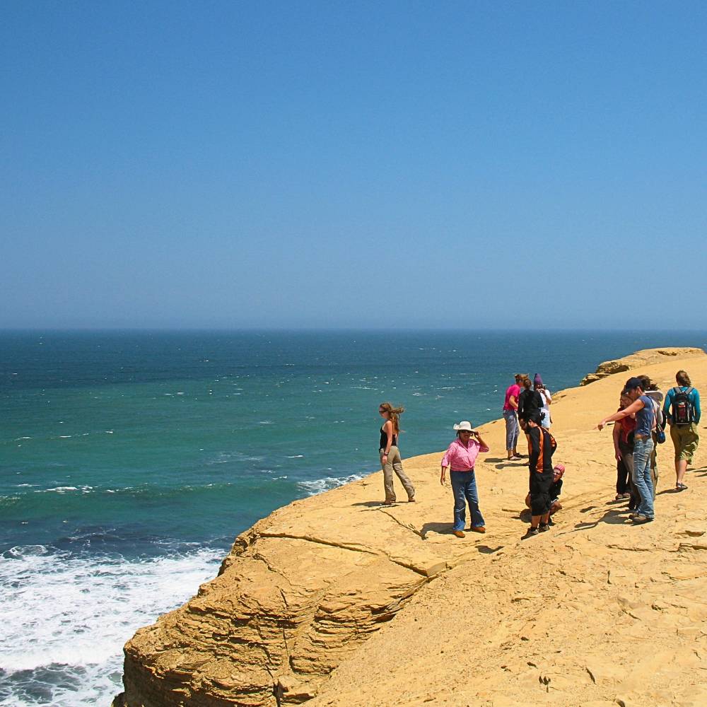 Visitors exploring the dramatic coastal cliffs of the Paracas National Reserve on a private tour from Lima.