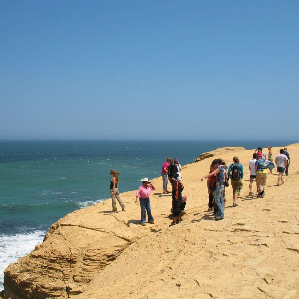 Visitors exploring the dramatic coastal cliffs and desert landscapes of Paracas National Reserve in southern Peru.