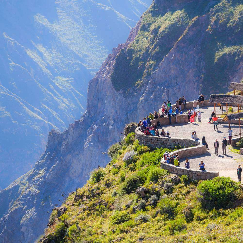 Viaggiatori che godono di panorami panoramici dal Cruz del Condor che sovrasta il drammatico Canyon del Colca durante il Tour del Canyon del Colca da Puno.