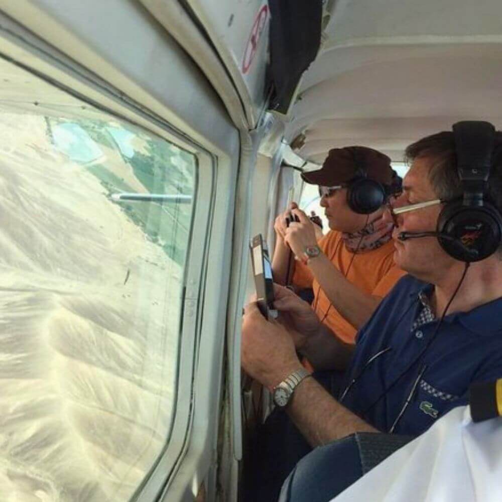 Passengers observing ancient Nazca and Palpa geoglyphs through the window of a sightseeing aircraft during an aerial tour.