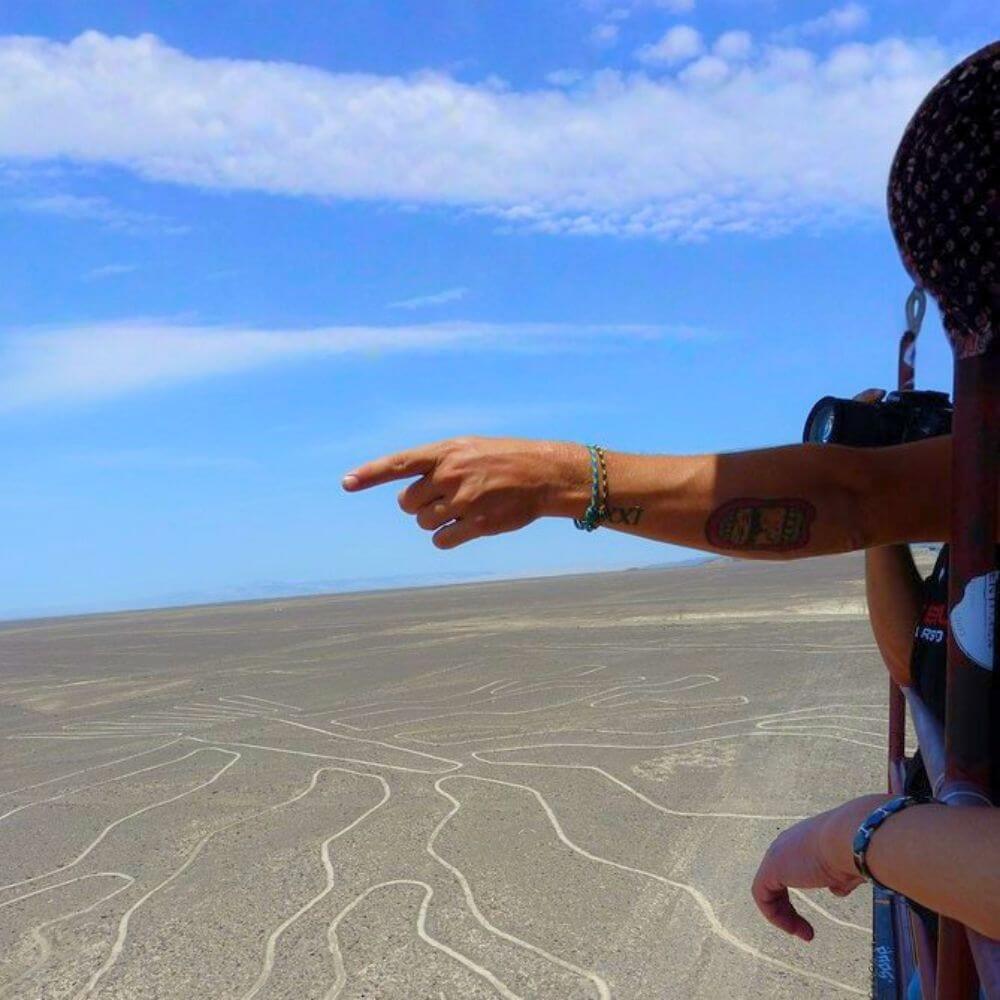 Tourist pointing at the famous Nazca Lines geoglyphs during a scenic flight over the Nazca Desert in Peru.
