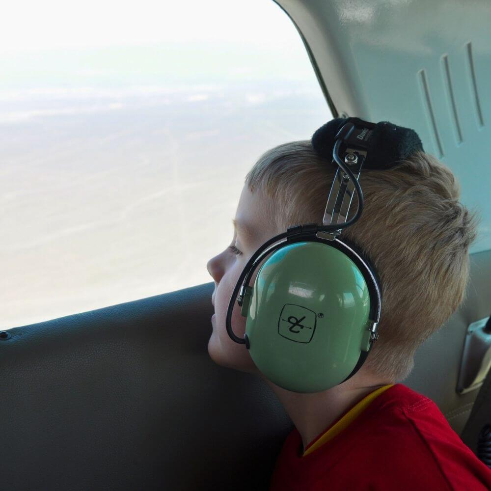 Young traveler looking out of an aircraft window during a Nazca Lines flight from Pisco Airport in Peru.