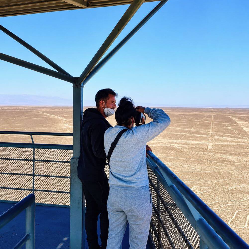 Travelers enjoying panoramic views of the Nazca Lines from an observation tower in the Nazca Desert, Peru.