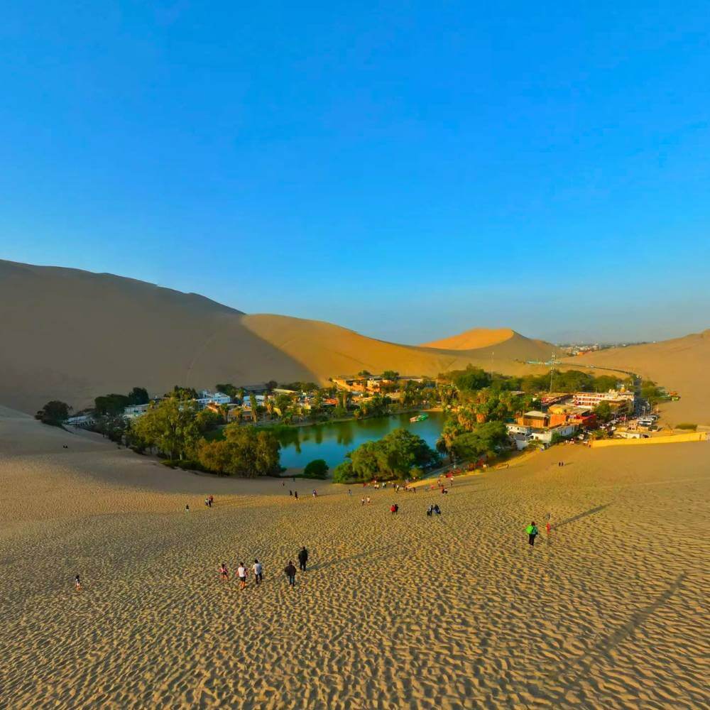 Panoramablick auf die Huacachina-Oase, umgeben von beeindruckenden Sanddünen im Süden Perus während der Huacachina Dune Buggy Tour.