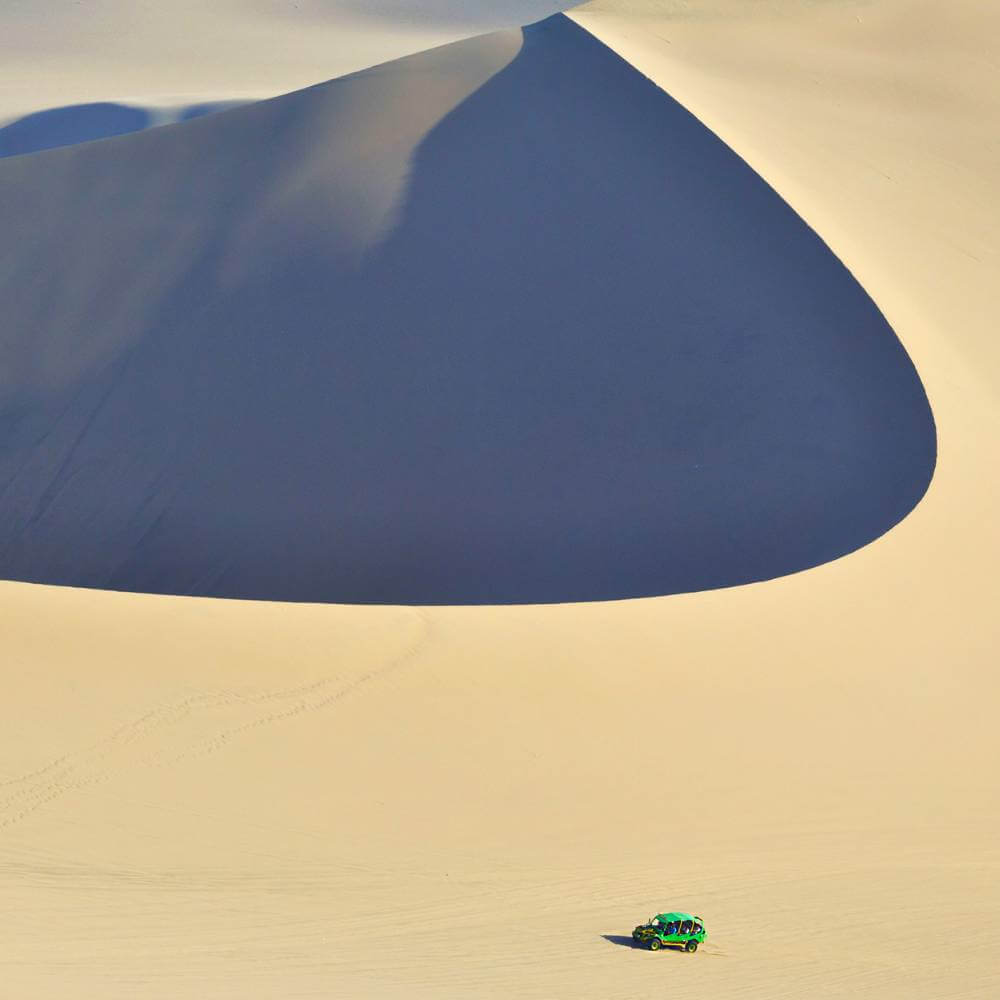Dune Buggy überquert die riesigen Sanddünen der Huacachina-Wüste in Peru mit dramatischer Wüstenlandschaft.