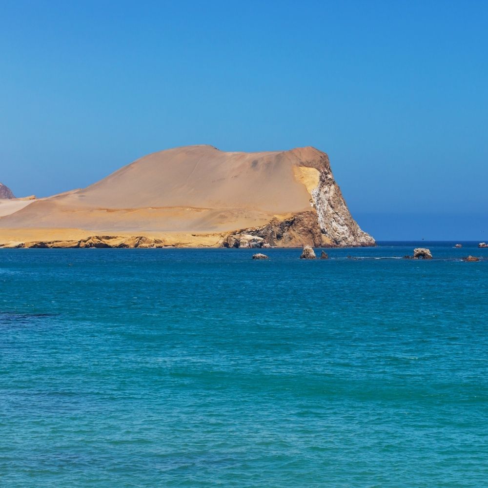 Spektakuläre Küstenklippen und türkisfarbenes Wasser der Paracas-Halbinsel, die während einer Paracas-Bucht-Tour in Peru gesehen werden.