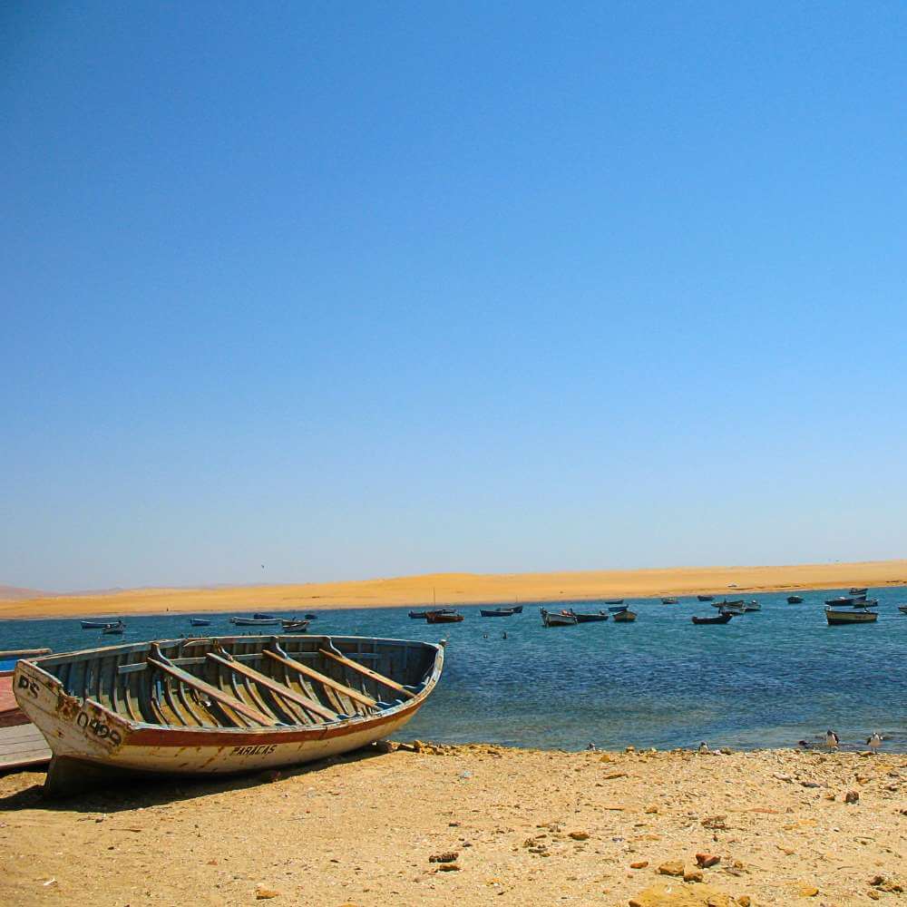 Traditionelle Fischerboote, die an der friedlichen Bucht des Fischerdorfs Lagunillas im Paracas-Nationalreservat, Peru, ruhen.