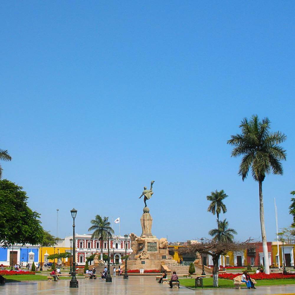 Plaza de Armas of Trujillo, Peru, with the Freedom Monument, palm trees, gardens, and colorful colonial buildings.